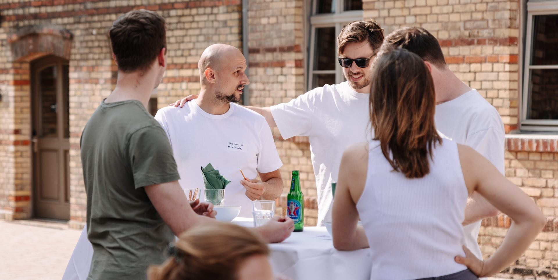 Photo of six people standing at a table outdoors at a company event, including two Minimise founders facing the camera