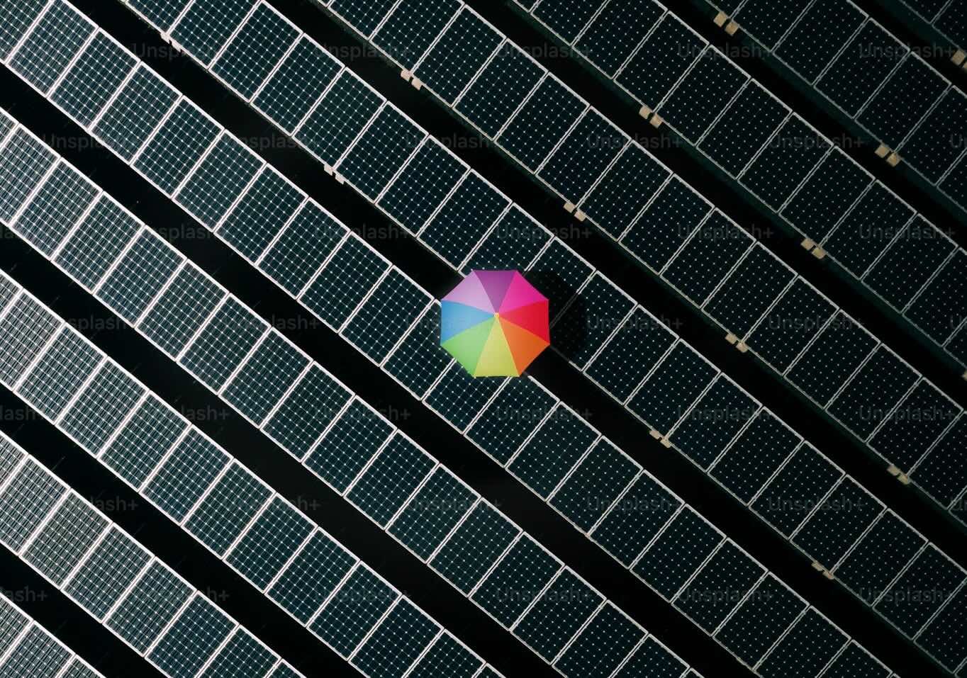 A colorful umbrella in a large array of solar panels, seen from above